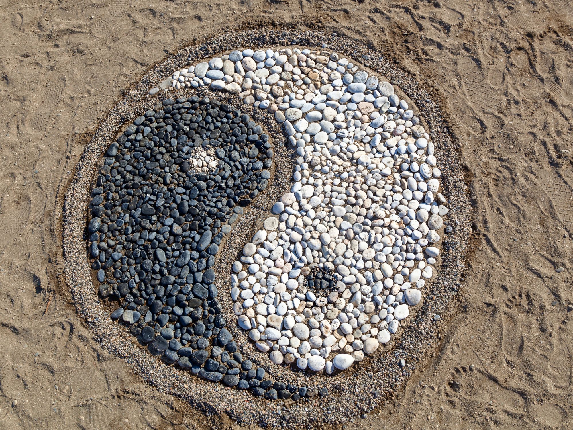 cailloux sur du sable représentant le symbole yin yang